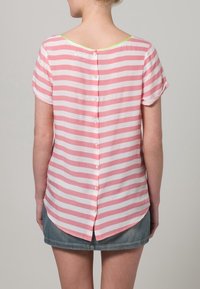 Kortärmad randig blus i ljusrosa och vitt med rundad nacke bak och knappstängning i mitten. Mjukt, lätt material.