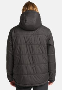 Giubbotto puffer nero con cappuccio, caratterizzato da un design trapuntato e una texture liscia. Il giubbotto ha maniche lunghe e un orlo leggermente curvato.