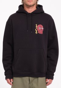 Hoodie noir en coton avec une poche avant. Présente un graphique de crâne rouge et jaune portant des lunettes de soleil sur la poitrine gauche.