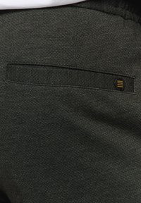 Dark gray fabric with a textured finish, featuring a back pocket and a small black label with yellow accents.