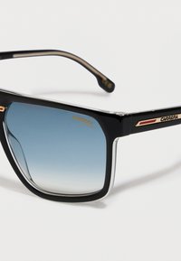 Črne sončarske očala Carrera s kvadratnim okvirjem, modrimi graduiranimi UV-zaščitnimi lečami ter logotipom z zlatimi detajli na templju in kotu leče.