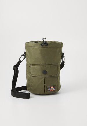 Compacte olijfgroene crossbodytas met voorvak met knoop, trekkoordsluiting, zwarte verstelbare band en Dickies-logo op de voorkant.