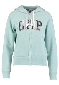 Sweat à capuche zippé couleur vert d'eau clair en tissu doux, avec un logo GAP argenté, des poches avant et des cordons avec embouts métalliques.