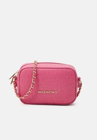 Sac bandoulière rose avec logo de marque embossé, chaîne dorée, fermeture éclair et forme rectangulaire. Texture lisse et couleur vive.