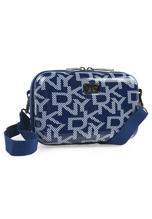 Bolsa rectangular de color azul marino con patrón geométrico blanco, acabado brillante, herrajes plateados y correa ajustable. Placa con logotipo en la parte frontal.