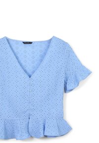 Blouse bleu clair à manches courtes avec un col en V, fermeture à boutons, motif œillet et ourlet volants. Fabriquée en tissu léger.