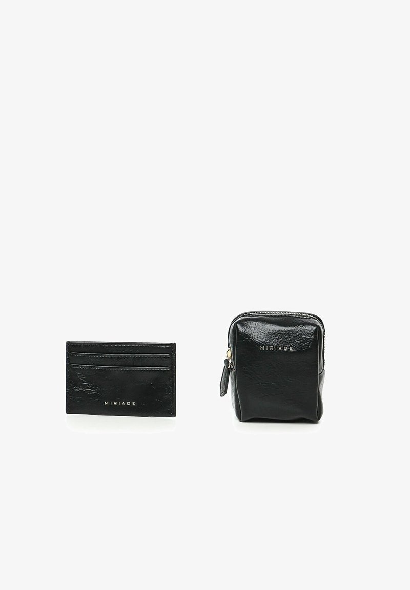 Portafoglio in pelle nera e pochette con zip, entrambi caratterizzati da una finitura rugosa. Marchio dorato sul fronte. Forme compatte e rettangolari.