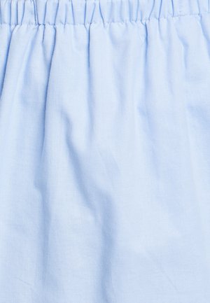 Gaiši zils audums ar mīkstu tekstūru, ar savelkamu šuvju pie jostas, kas norāda uz elastīgu dizainu.