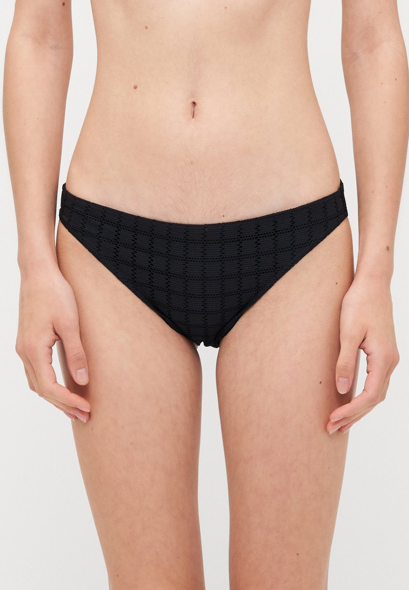 Black bikini bottom featuring a textured checkered pattern, with a smooth waistband and medium coverage. Made of lightweight swim fabric.