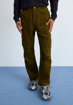 Olivengrønne corduroy cargo bukser med flere sidelommer, loose fit og knaplukning. Sættet er kombineret med grå sportssko.