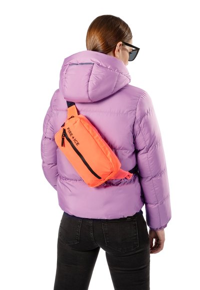 Fialová péřová bunda s kapucí, spárovaná s oranžovou crossbody taškou se černým zipem. Taška má kontrastní popruh.