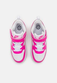 Nike tenisice s bijelom podlogom, svijetloružičastim naglascima i čičak trakama. Perforirano prednje područje za prste i teksturirana potplat. Sadrže bijele vezice.