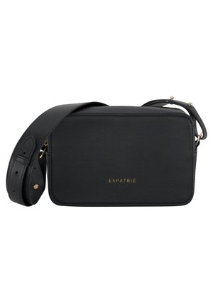 Schwarze Leder-Crossbody-Tasche mit rechteckiger Form, goldenen Beschlägen und der Markeninschrift "EXPATRIÉ" in der Mitte. Verstellbarer Gurt inklusive.