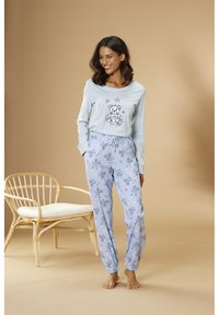 Svetlomodrá dlhá blúzka s grafickým zobrazením medvedíka a hviezdičiek; v kombinácii so svetlomodrými pyžamovými nohavicami s vzorom medvedíkov a hviezdičiek.