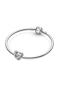 Bracciale d'argento con un charm a forma di cuore con dettagli intricati, chiusura a scatto e una perla tonda con il nome del marchio inciso.