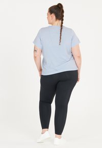 Ljusblå t-shirt med kort ärm, kombinerad med svarta leggings. Har en avslappnad passform och en mjuk textur. Vita sneakers fulländar outfiten.