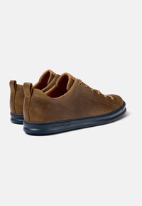 Sneakers in pelle marrone dalla forma arrotondata, con suola blu navy e asole per i lacci abbinate. Presentano un discreto logo Camper sul lato.