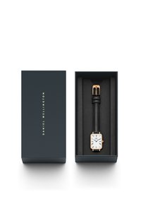 Square white watch with black leather strap, gold-tone hardware, and roman numeral markers, presented in a navy box with a black foam insert.