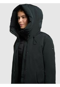 Tmavě zelená, zateplená parka s velkou kapucí, zipem a patentkami, a bočními kapsami; hladký povrch s minimálním zdobením.