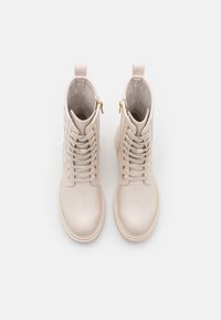 Botas de tobillo de cuero rosa claro con herrajes dorados, punta redonda, cordones en la parte delantera y cremalleras laterales. Textura suave con detalles de costura.