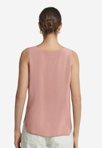 Ärmlös blus i mjuk rosa tyg, med en slät yta, rund halsringning och en böjd nederkant bak.