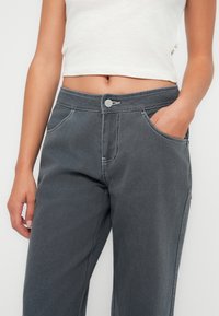 Grå denimbyxor med en avslappnad passform, med knappstängning och framfickor, prydda med kontrasterande vit sömnad.