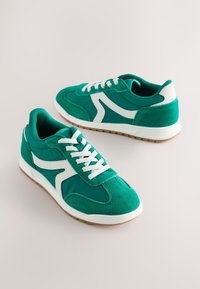 Baskets en daim vert avec des accents blancs, dotées d'un design à lacets et d'un col rembourré. Semelle en caoutchouc à motif texturé pour une meilleure adhérence.