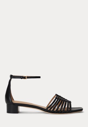 Sandale en cuir noir avec un petit talon carré, dotée d'un design ouvert à l'avant et de détails de sangles entrecroisées, boucle ajustable à la cheville.