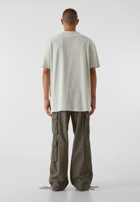 Lysegrå bomulds T-shirt med korte ærmer og en afslappet pasform, parret med olivengrønne cargo bukser med sidelommer og justerbare kanter.