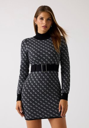 Abito a righe in bianco e nero con maniche lunghe, collo alto e silhouette aderente, caratterizzato da una ampia cintura nera con fibbia argentata.