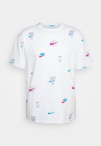 Camiseta blanca de algodón con logotipos y eslóganes de Nike en azul, rosa y gris esparcidos, con mangas cortas y cuello redondo.