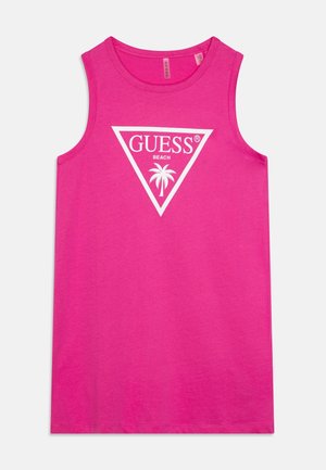 Lyserød ærmeløs top med hvid "GUESS BEACH"-logo og palmetræsgrafik inde i en omvendt trekant foran.