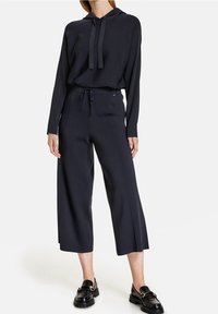 Mörkblå hoodie med dragsko i halsen och avslappnad passform, tillsammans med matchande vida byxor med en bekväm midja och slankt utförande.