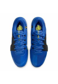 Par de zapatillas deportivas azules con tiras laterales negras, cordones azules y plantillas amarillas que muestran un logotipo estilizado y texto.