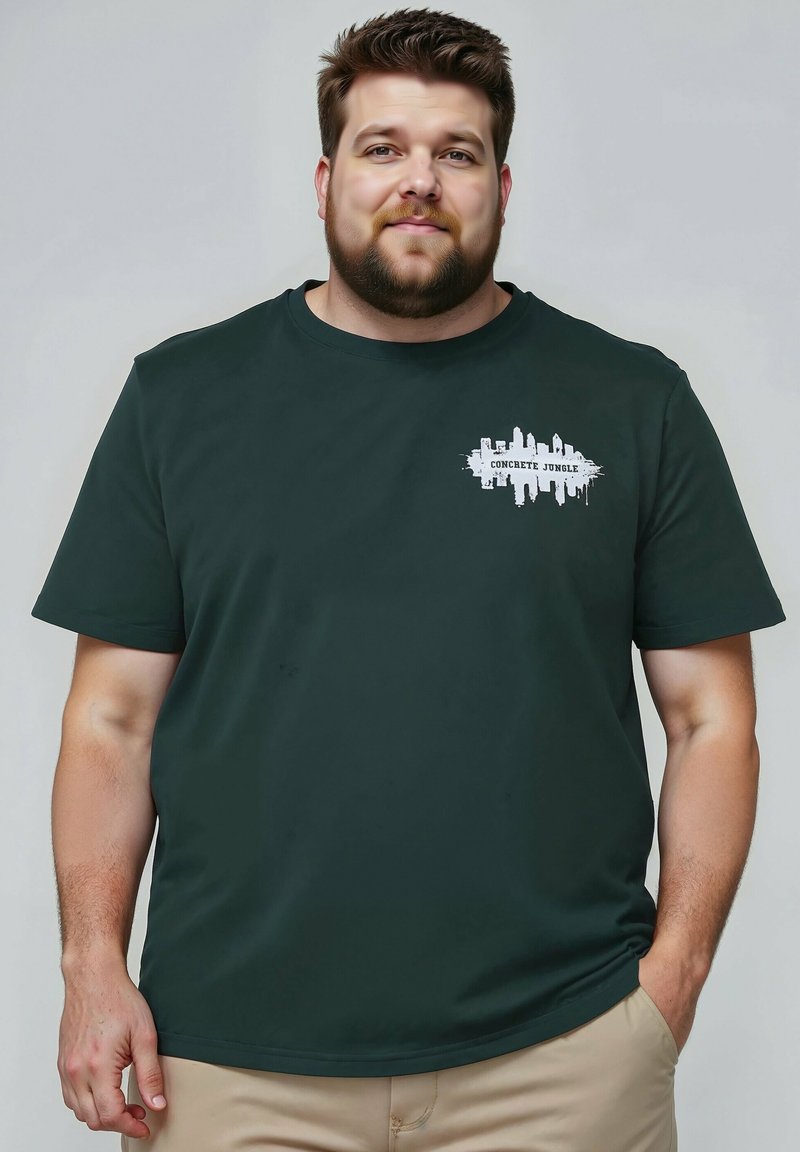 Tmavě zelené bavlněné tričko s bílou grafikou, na níž je nápis "BETONOVÁ JUNGLE" a design siluety města na hrudi.