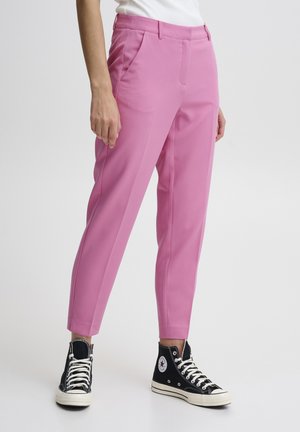 Pantaloni rosa realizzati in tessuto liscio con una vestibilità tailored, dotati di tasche laterali e di lunghezza cropped, abbinati a sneakers nere alte.