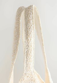 Poignées de sac tissées de couleur crème, fabriquées en tissu texturé, avec un design tressé et des bords lisses, idéales pour porter des objets.