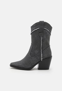 Botas de vaquero de denim gris con punta afilada y tacón alto. Presentan bordes deshilachados y un diseño de costura a lo largo del eje superior.