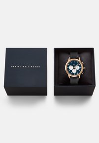 Orologio con cinturino in pelle nera, cassa in oro rosa, quadrante blu, tre sottodial e indici delle ore dorati, presentato in una scatola blu navy.