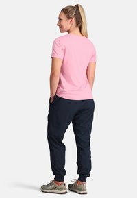 Rosa Kurzarmshirt, marineblaue Jogginghose und graue Sneakers. Die Jogginghose verfügt über Seitentaschen und elastische Bündchen für eine lässige Passform.