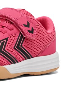 Scarpa sportiva rosa con tomaia in mesh, dettagli neri e una fascia con chiusura a velcro. La suola è bianca con un battistrada in gomma testurizzata.