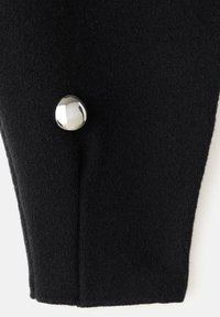 Un tessuto nero con una texture liscia presenta un bottone rotondo e riflettente di colore argento su un lato, accentuando la forma e il design del capo.