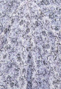 Δυοσμένο μωβ ύφασμα με πυκνά τοποθετημένο μικρό σκούρο μωβ και μαύρο λουλουδάτο σχέδιο και ορατές κάθετες ραφές.