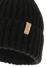 Black knitted beanie with a ribbed texture, featuring a leather tag with the brand name sewn on the side. Soft and warm material.