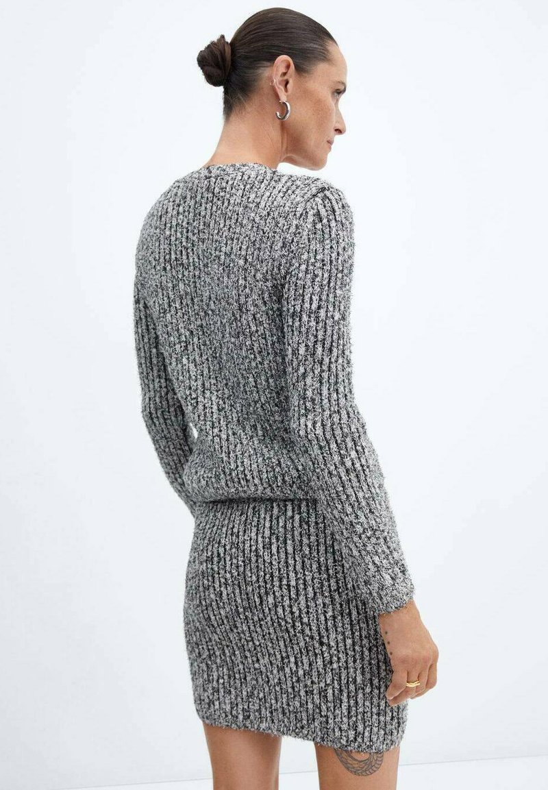 Pull en maille côtelée grise et jupe mini assortie, présentant un motif texturé. Le tissu semble doux et extensible, avec une coupe ajustée.