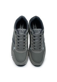 Graue sportliche Sneakers mit synthetischem Obermaterial, Schnürverschluss, gepolstertem Kragen, Logo auf der Zunge, Gummisohle und strukturierten Bereichen für besseren Grip.