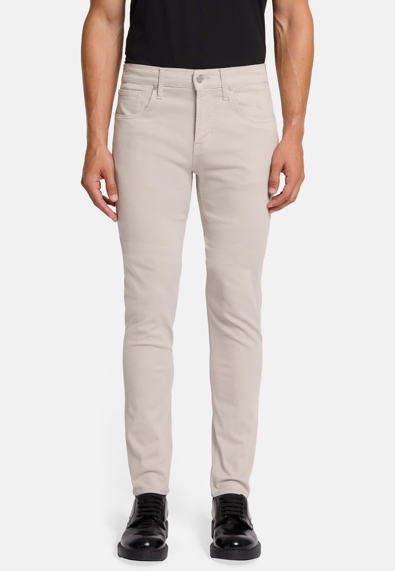 Lichtbeige slim-fit spijkerbroek van denim, met voorzakken, een ritssluiting met knoopsluiting en een gladde textuur. Gemaakt in combinatie met zwarte schoenen.