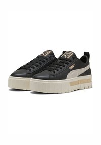 Sneakers in pelle nera con suola platform spessa color crema, caratterizzati da un design testurizzato e il logo Puma sul lato e sulla linguetta.
