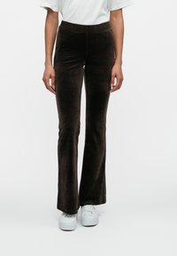 Brown flared pants made from soft, textured fabric with a high waistband, paired with white sneakers for contrast.