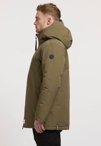 Olivgrön huva jacka med en slät yta, med en rund logotyp på ärmen, justerbara dragsko, och rak passform.